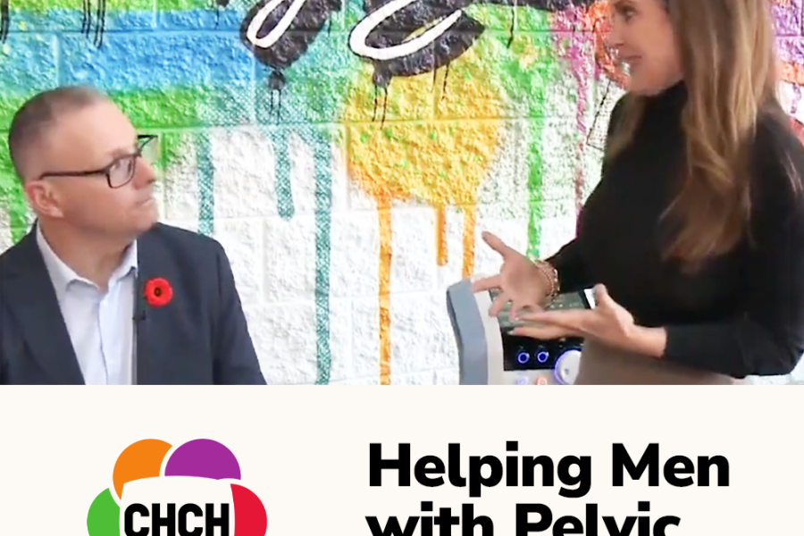 A woman speaking to a man, discussing pelvic floor health, with a colorful mural in the background and a device on the table.