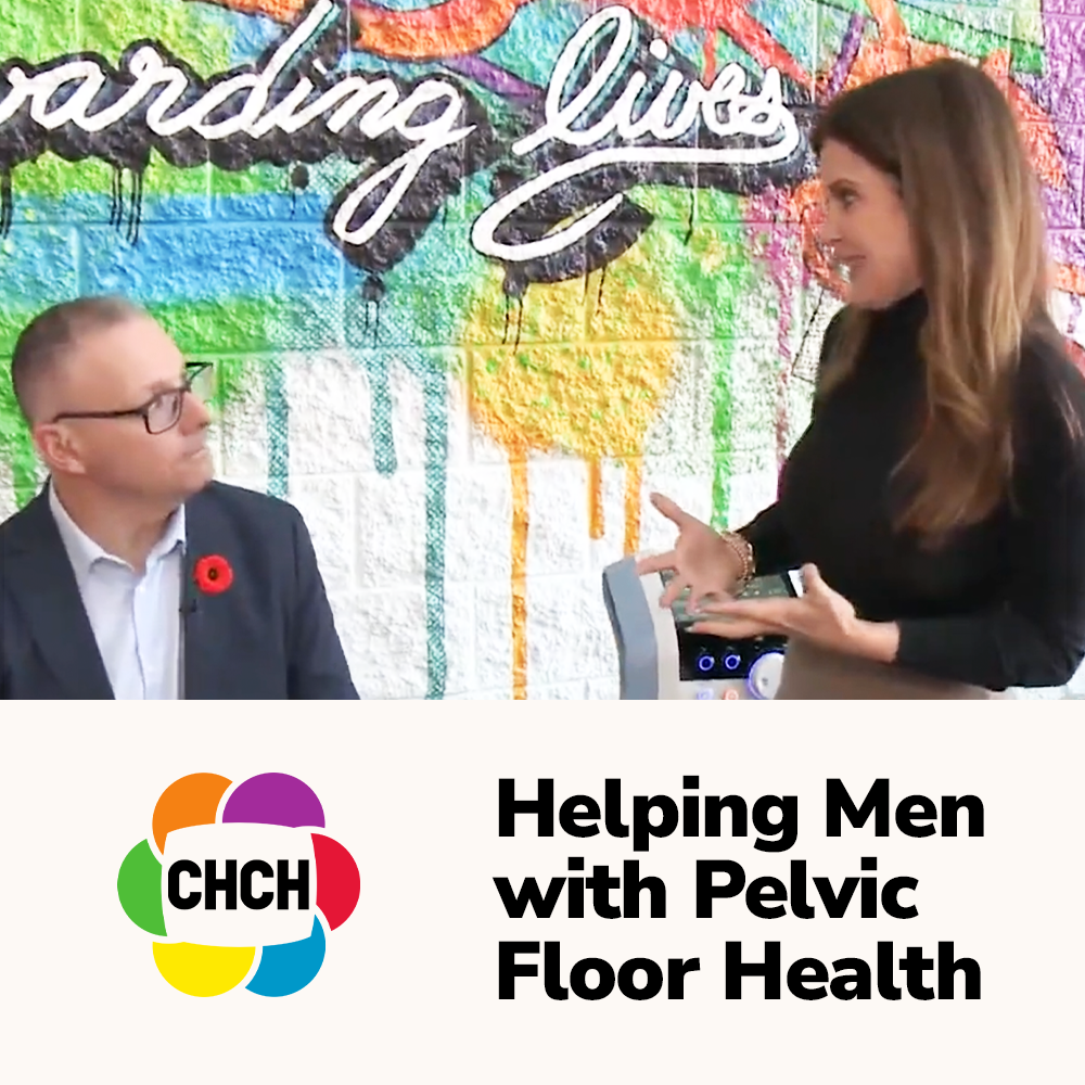 A woman speaking to a man, discussing pelvic floor health, with a colorful mural in the background and a device on the table.